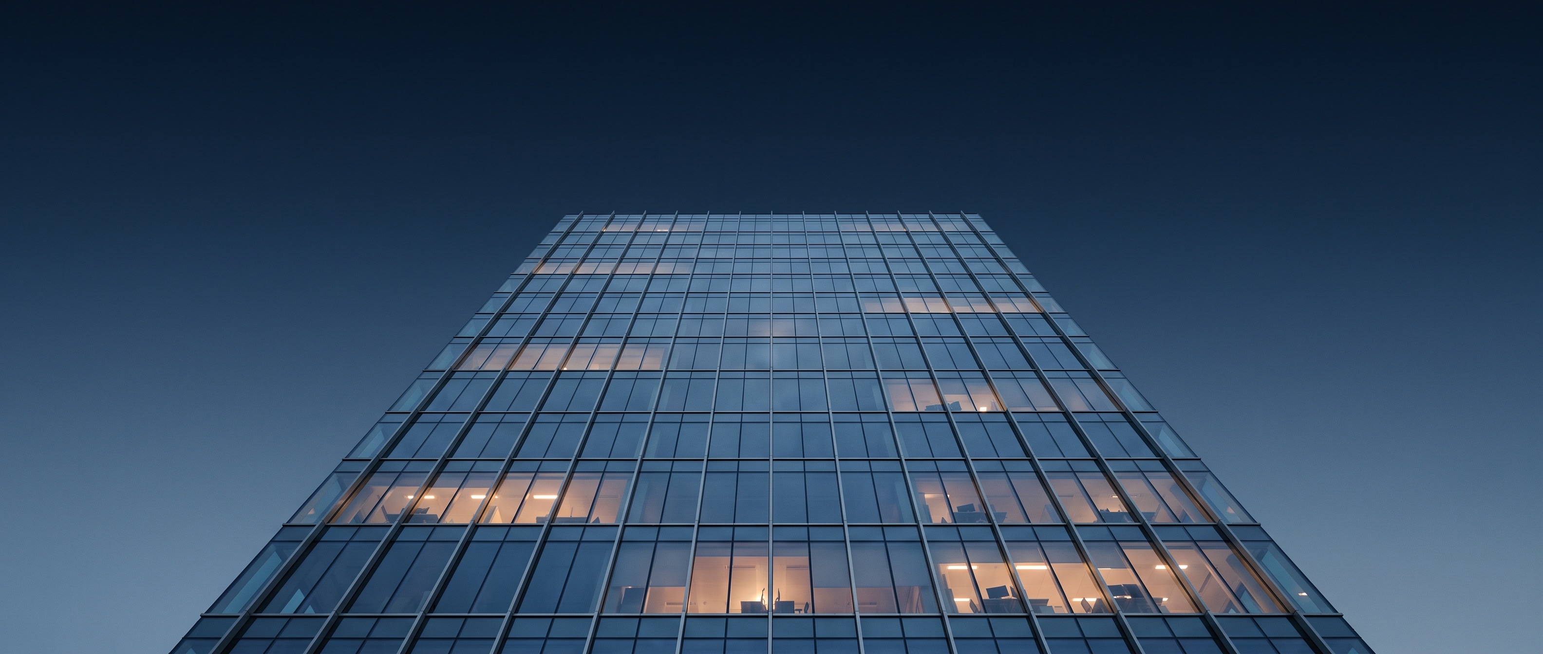Torre de oficinas de cristal al atardecer, tonos azules